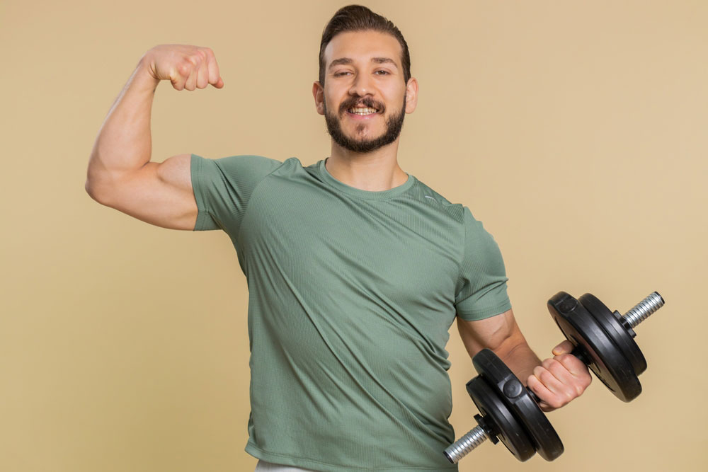 Sportsman guy with dumbbell on beige background